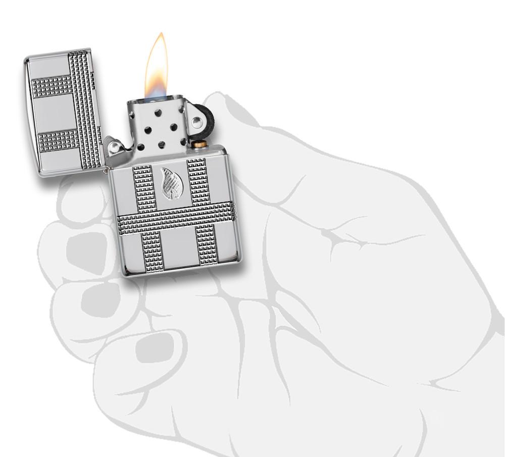 Geometric Design High Polish Chrome Windproof Lighter with its lid open and lit, in hand