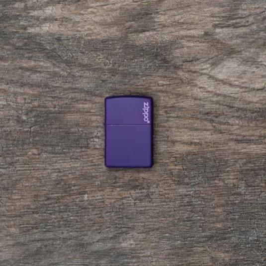 Lifestyle image of Purple Matte Zippo Logo windproof lighter laying flat on a wooden background 