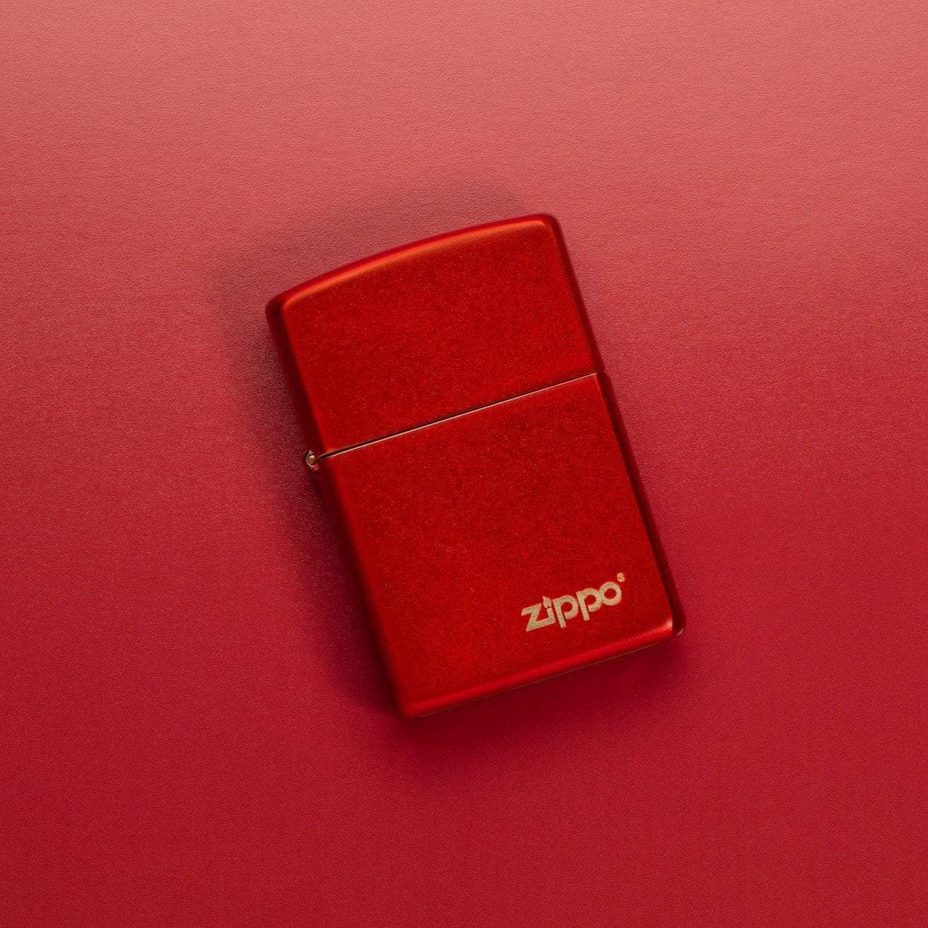 Lifestyle image of Classic Metallic Red Matte Zippo Logo Windproof Lighter laying on a red surface